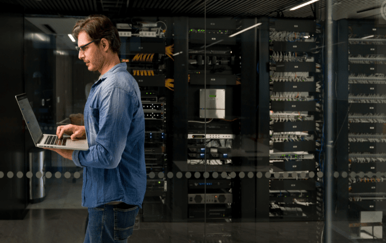 An image of a male on a laptop within a data center